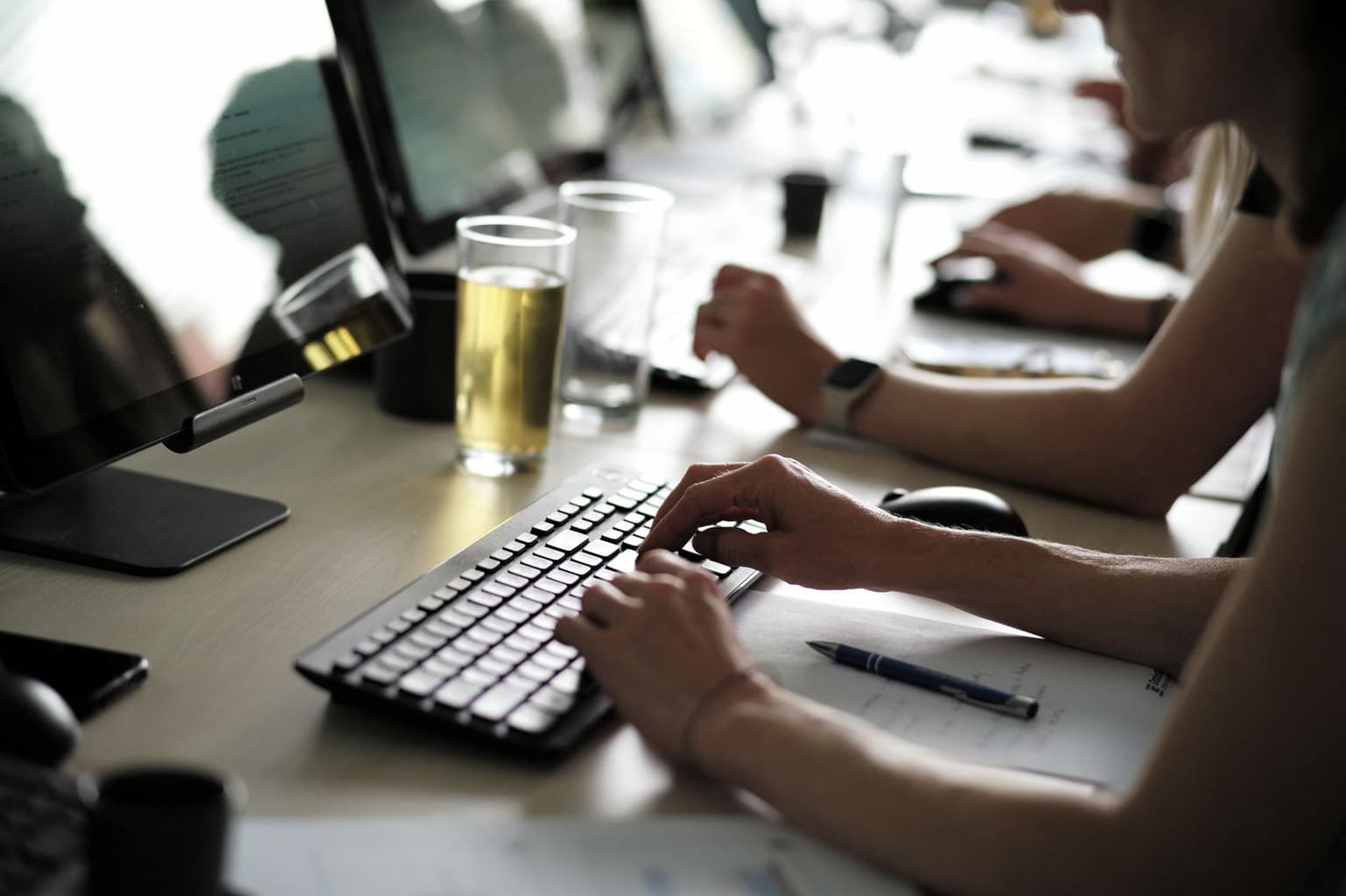 Ruce účastníka na klávesnici a poznámky vedle monitoru s analýzou